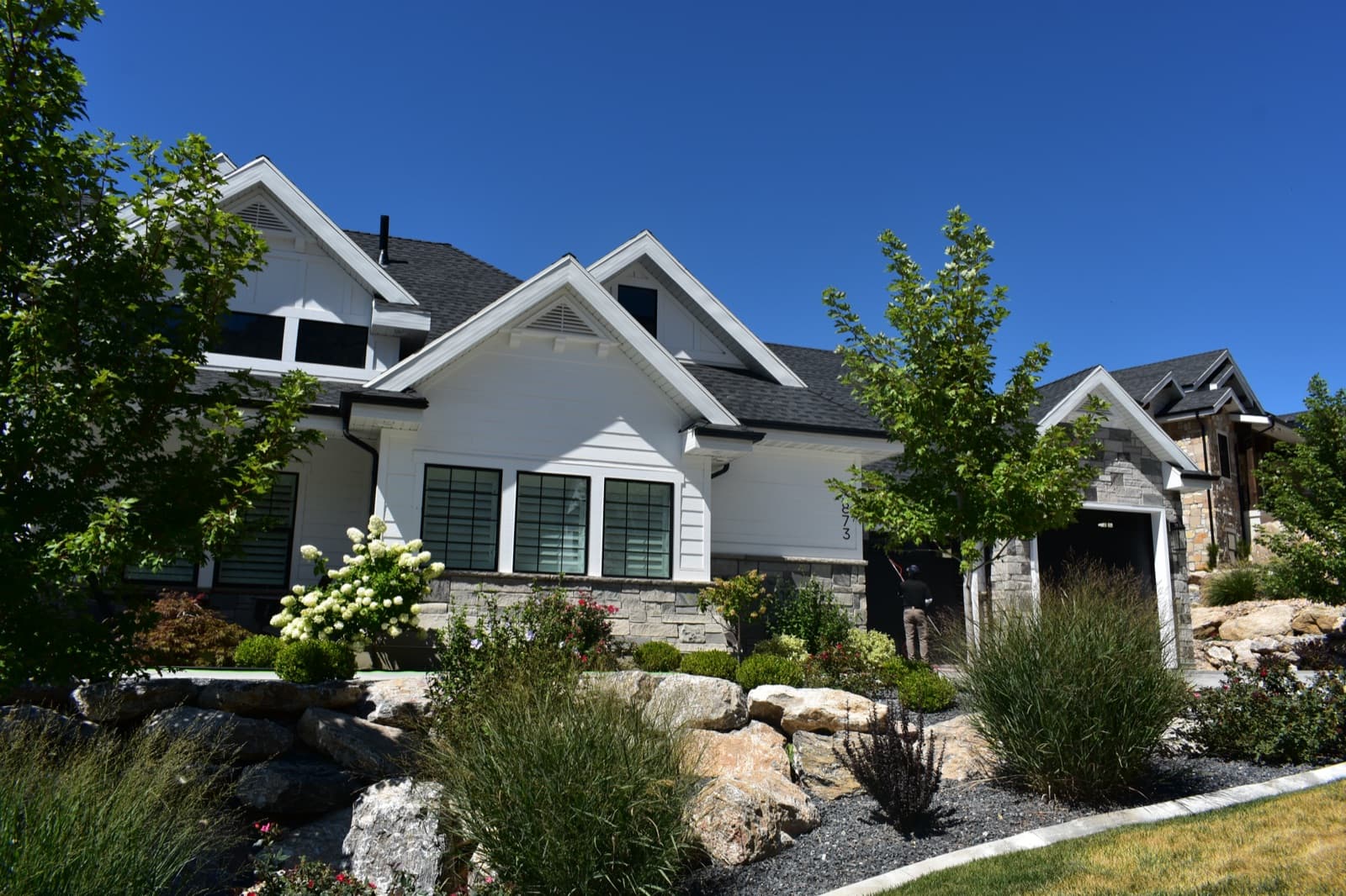 White cottage-style home with clean windows and lush rock landscaping