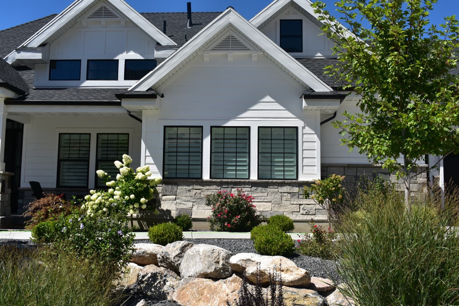 White craftsman home with freshly cleaned windows and colorful landscaping in Northern Utah