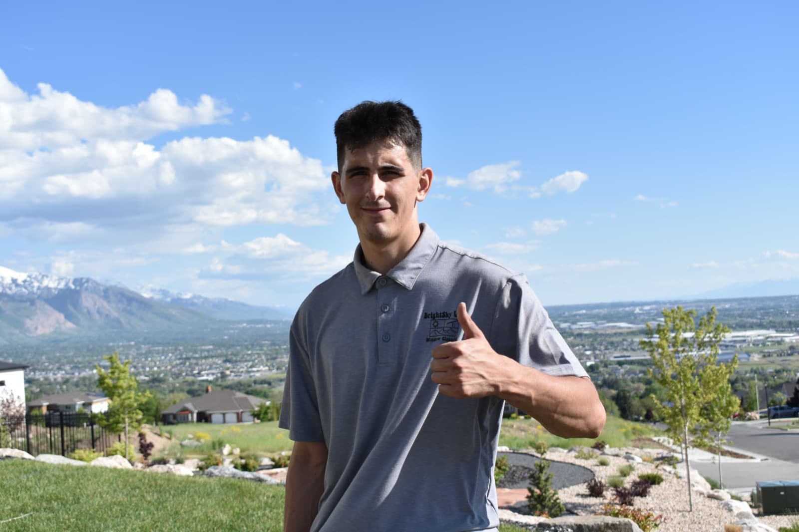 Smiling Crystal Cleaning technician giving a thumbs up with the Northern Utah valley behind him