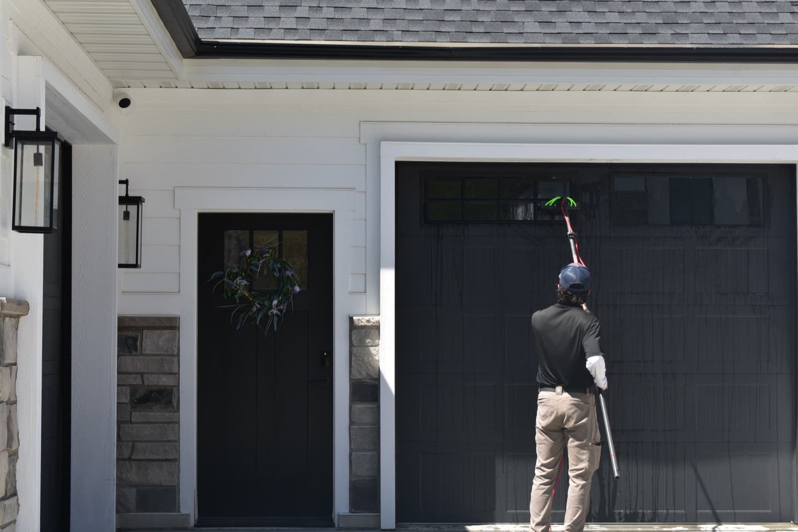 Technician squeegeeing garage door windows on a modern farmhouse
