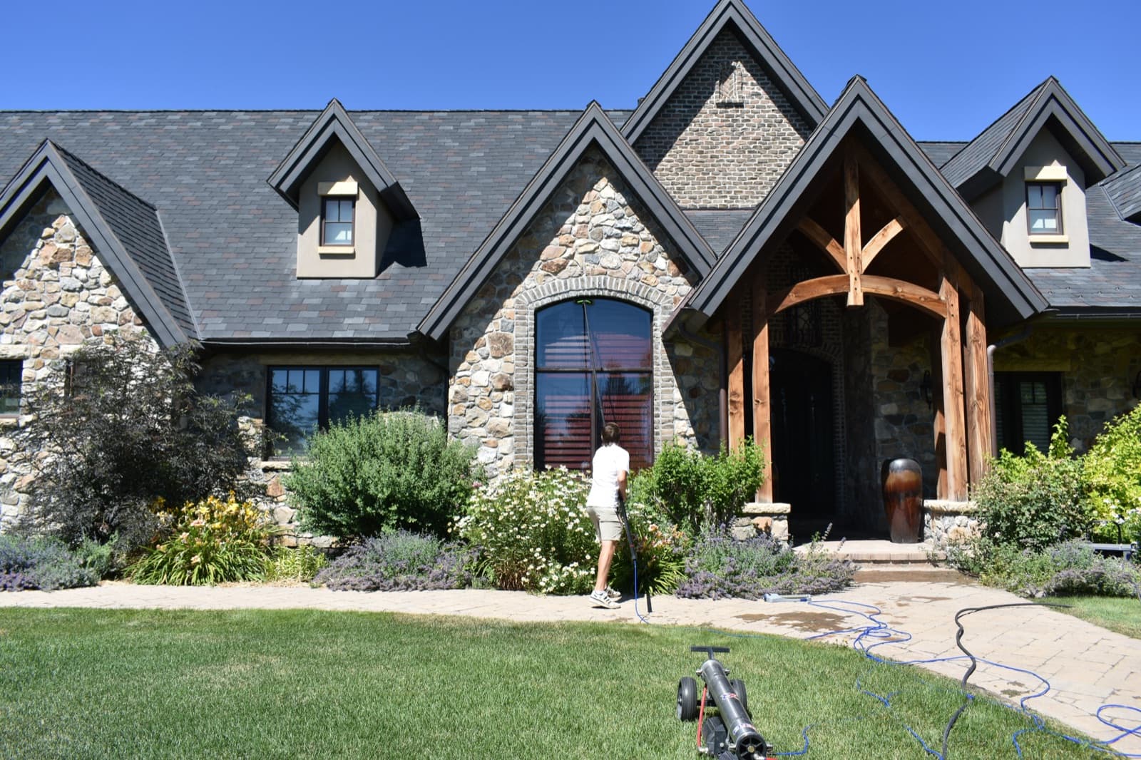Technician cleaning an arched window on a stone mountain home in Utah