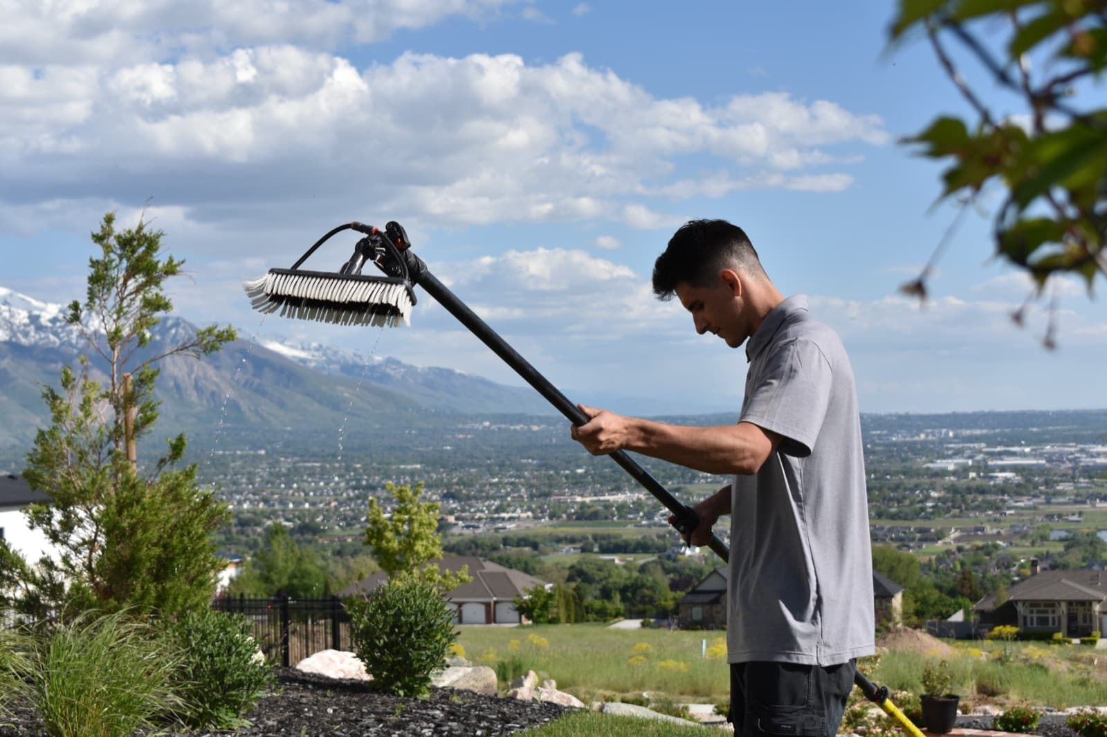 Crystal Cleaning technician with a water-fed pole brush overlooking the Wasatch Front valley in Northern Utah